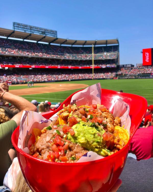 Image of a red Angels helmet filled with Nachos in front of a green baseball field.