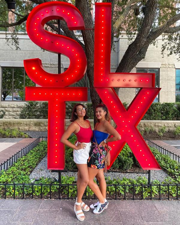 Two friends posing in front of the SLTX sign at Sugar Land Town Square