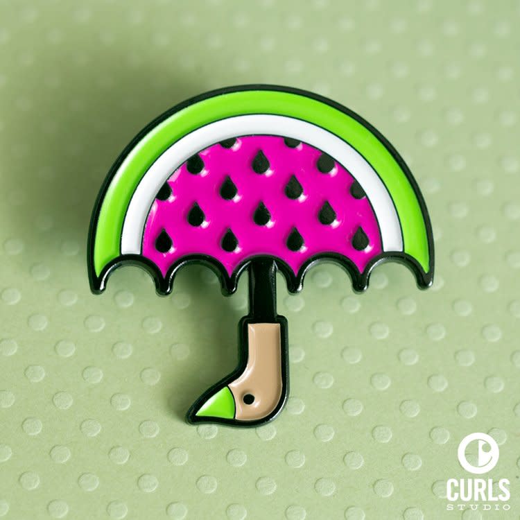 Brightly colored green and pink enamel pin shaped like an umbrella with duck face handle