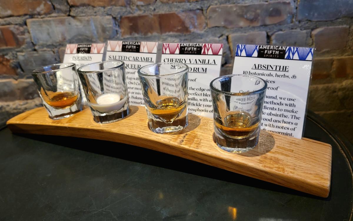 A flight with four spirits: Absynthe, Rum, Liqueur, and Bourbon.