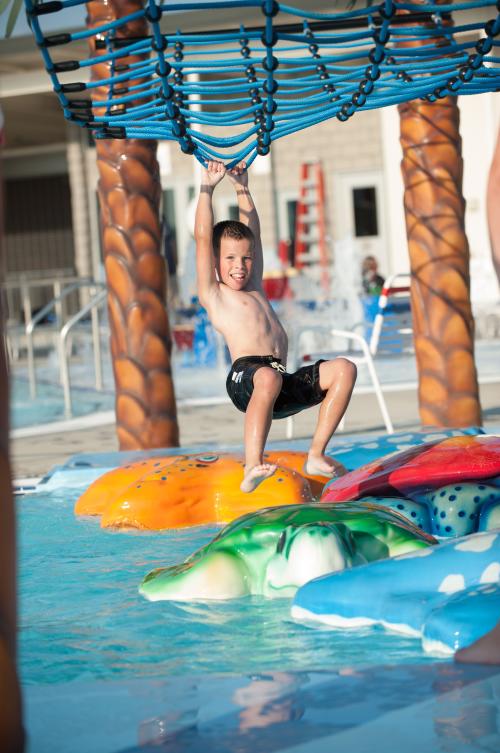 Kid swinging along the floating path at Freedom Springs Greenwood Aquatics Park in Johnson County
