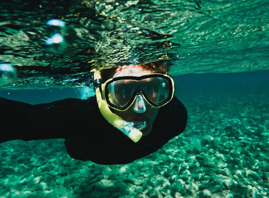 A snorkeler swims over a rocky lake bed in the crystal clear waters off the shore of Mackinac Island