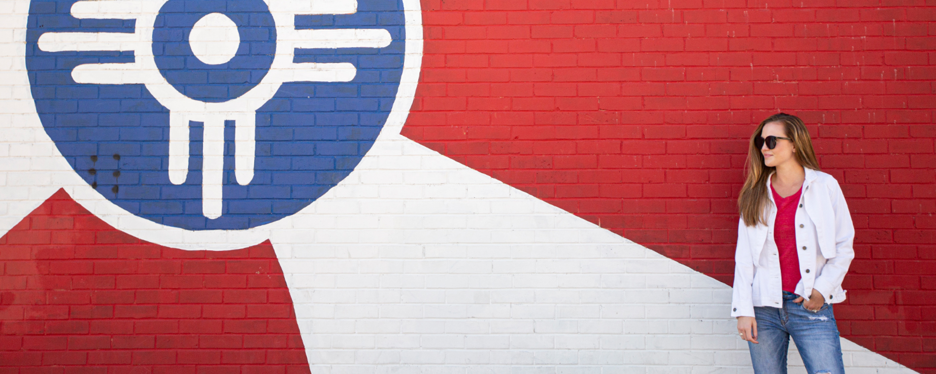 A woman stands in front of a Wichita Flag mural painted on the side of a building