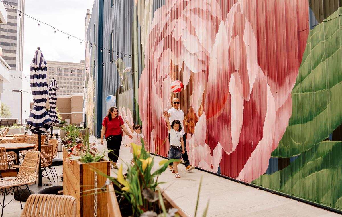 family walking by a restaurant and a mural
