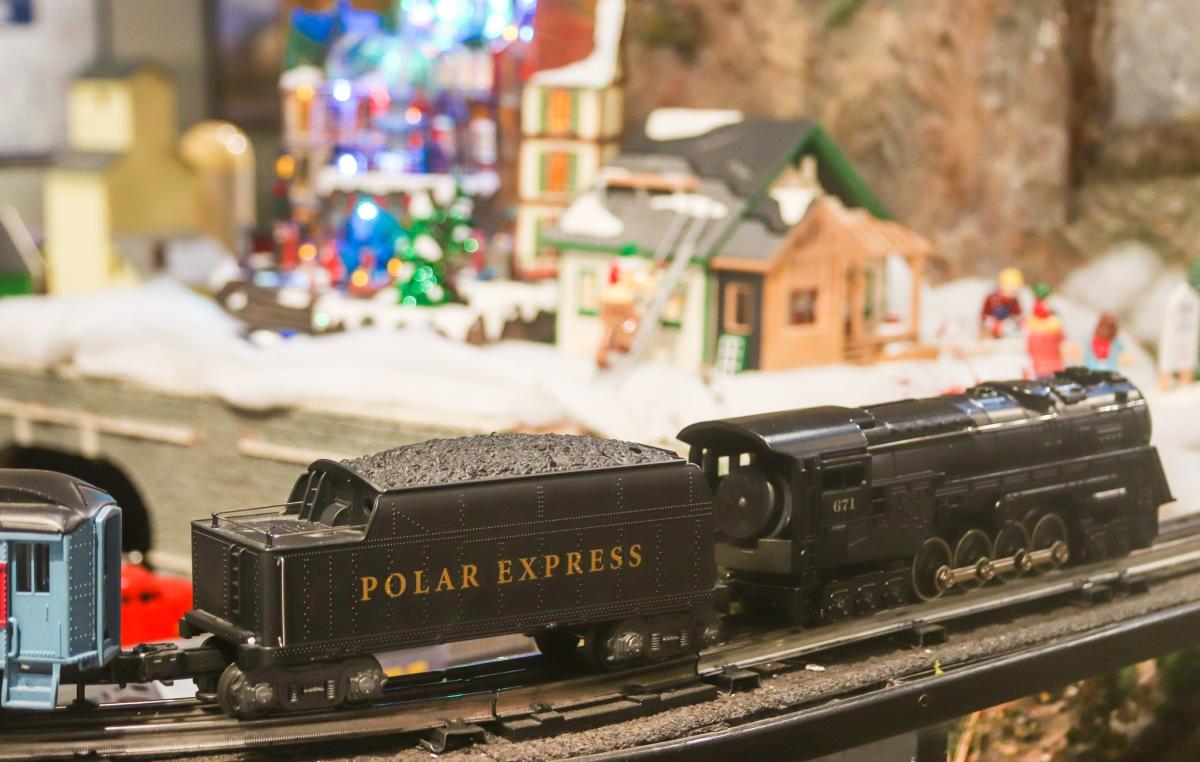 A model train rides through a Christmas Village