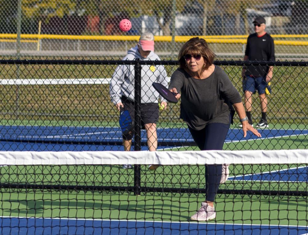 Woman hitting a pickleball at an outdoor park