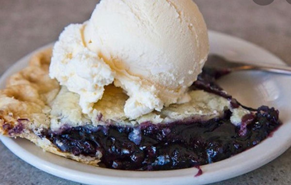 a scoop of vanilla ice cream on top of a slice of blueberry pie