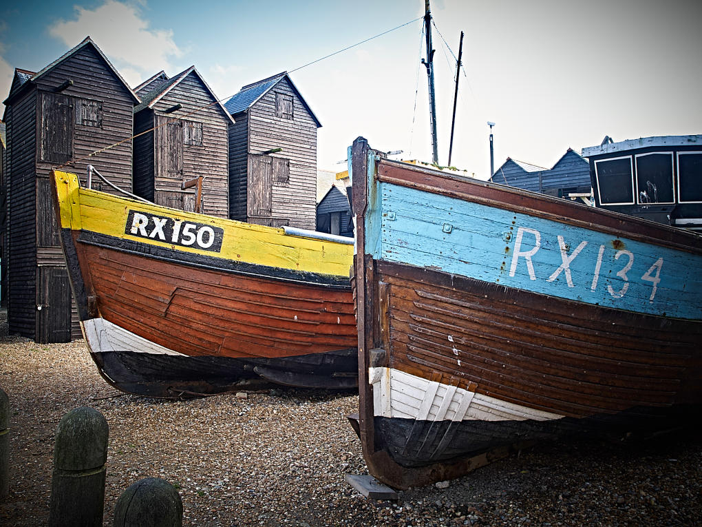 Two fishing boats moored on the shingle beach at Hastings with fishermans huts in the background