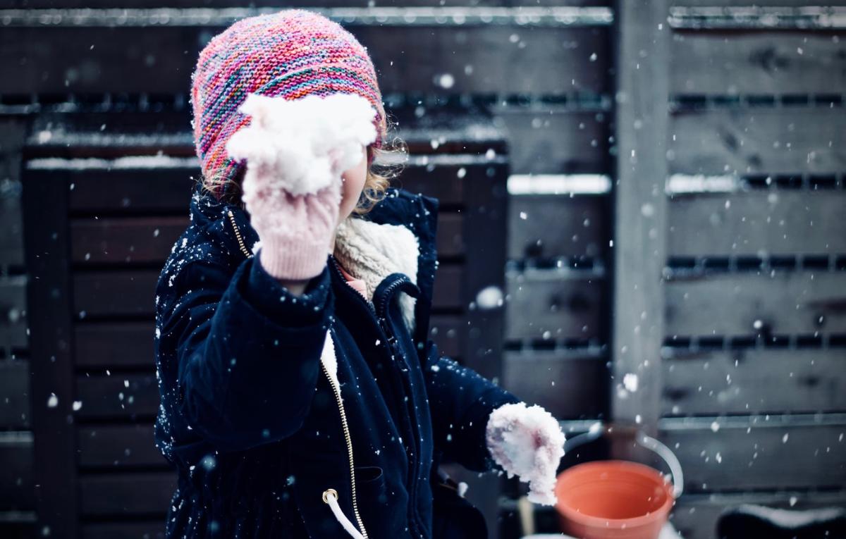 Small child throwing a snowball in the snow during winter