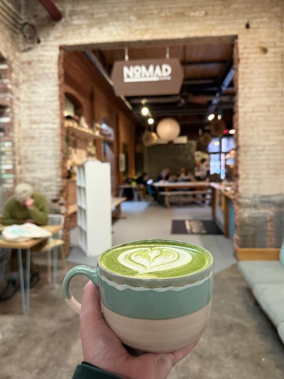 Hand holding a cup of matcha inside Nomad near the Burlington waterfront