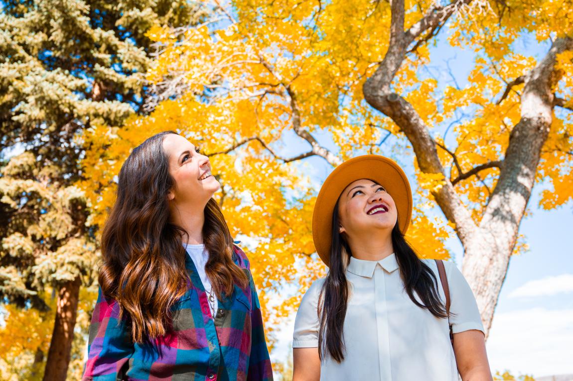Two women look up at the yellow leaves of a tree in Golden Colorado during the fall season.