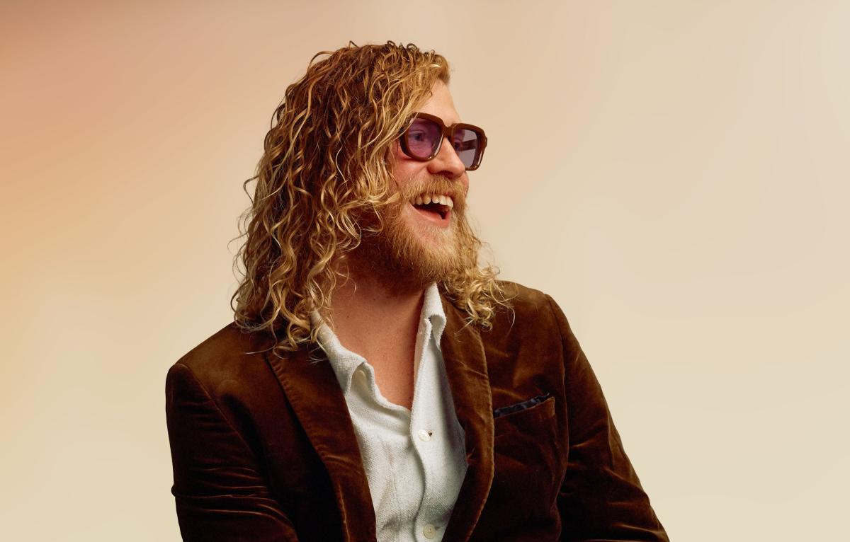 Musical artist Allen Stone poses for a photo while smiling and wearing sunglasses