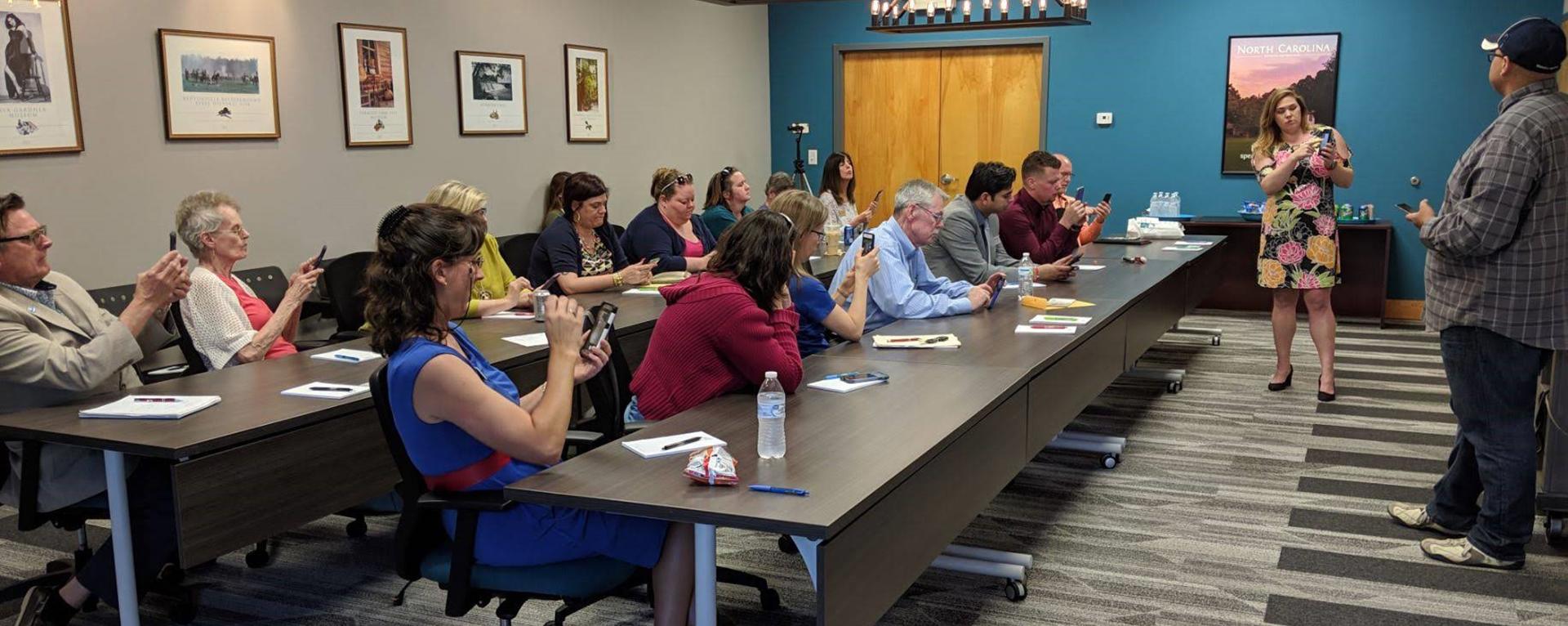 A group of Hospitality Association members try out a new app on their phones during a guest presentation.
