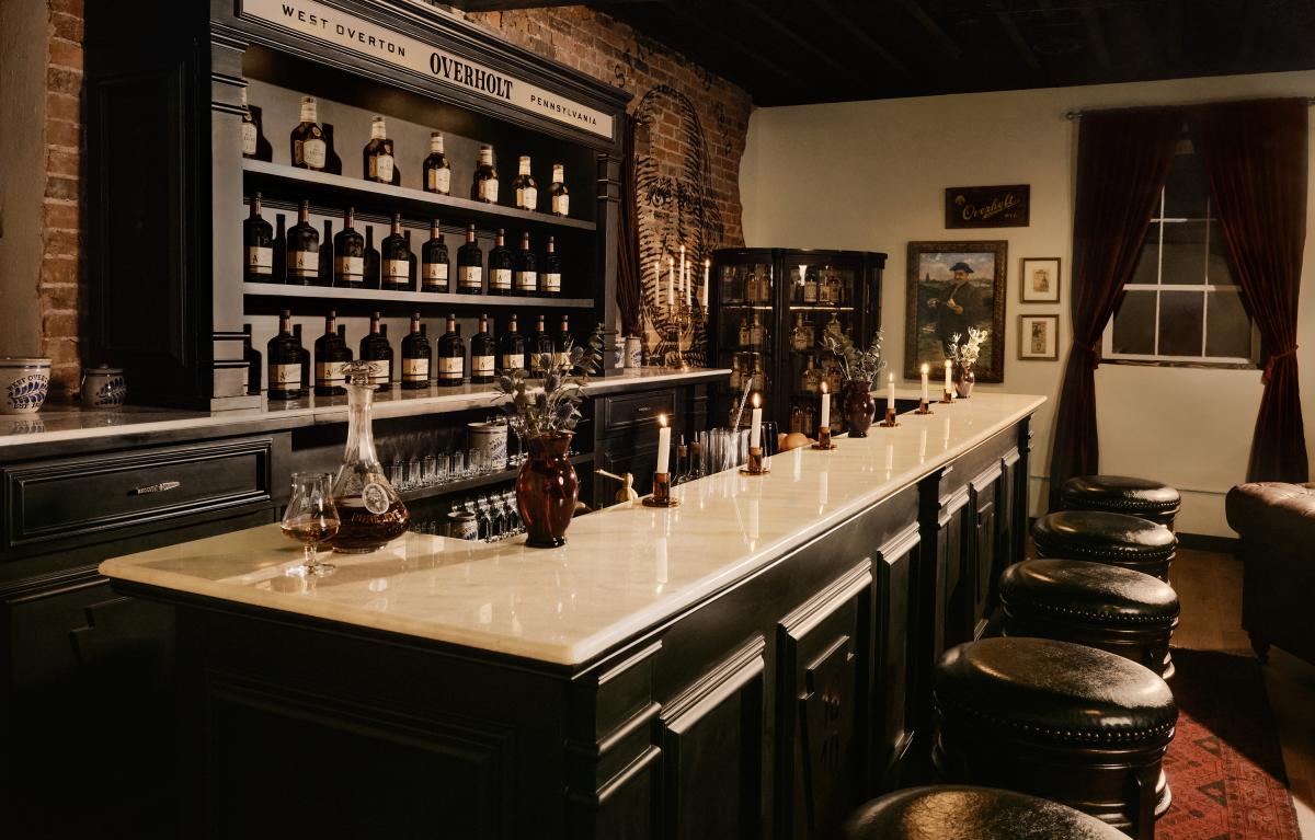 The Overholt Stateroom, a vintage-inspired lounge that pays homage to the origins of Overholt™ whiskey, features a modern bar, antique furniture and decor, vintage and modern bottlings, and a mural of Abraham Overholt.