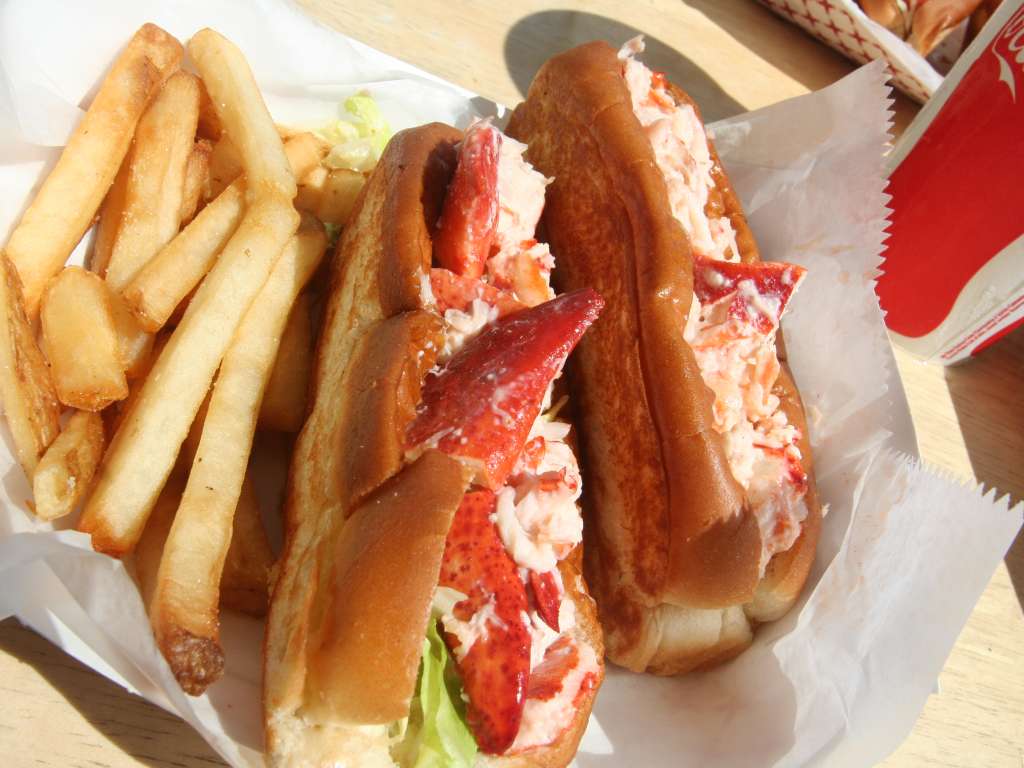 Delicious lobster roll with fries and a soda.