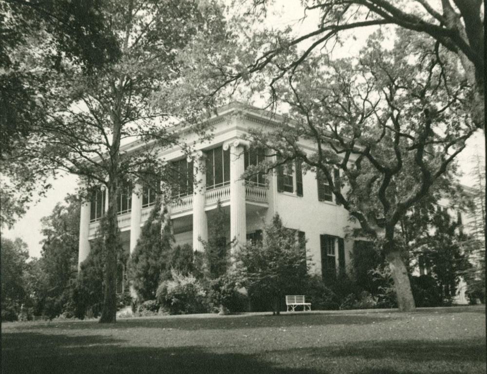 Historic black and white photograph of the exterior of Texas Governor's Mansion with four white columns and a grassy lawn