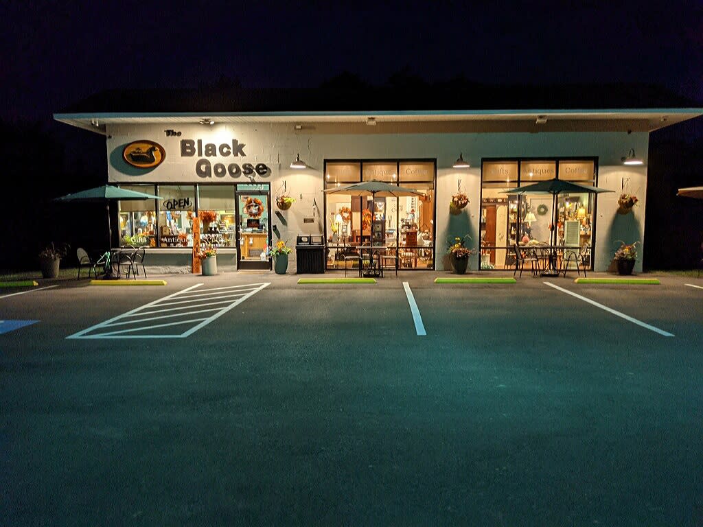 Image is of the outside, front facade of The Black Goose coffee shop at night.