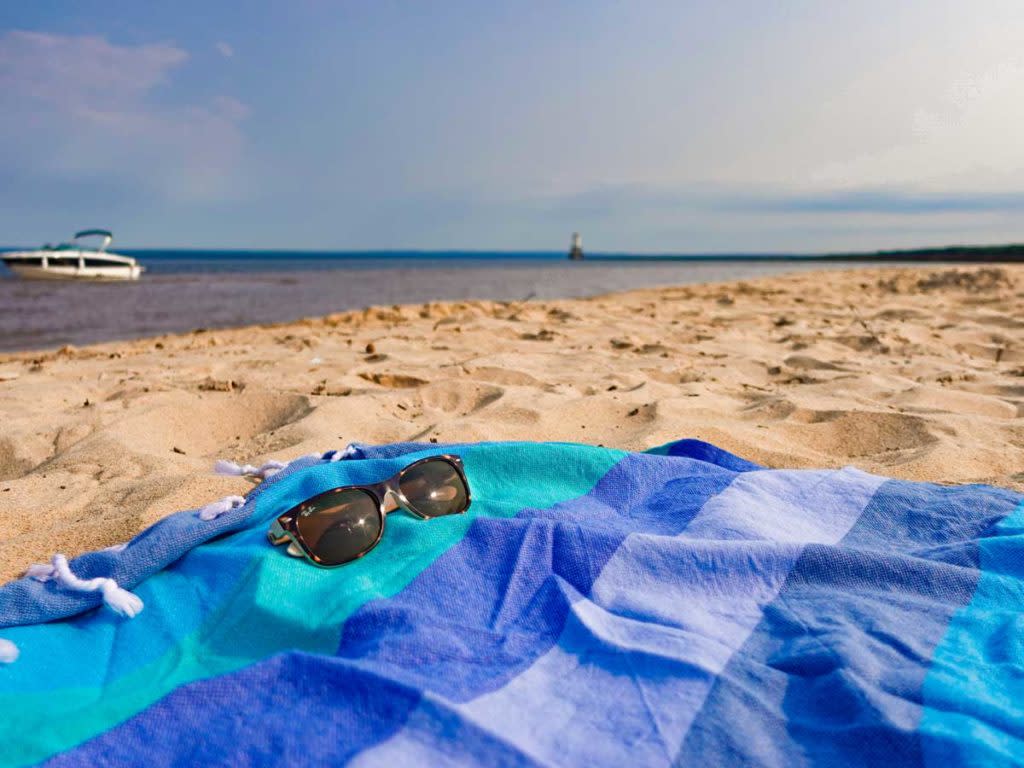 sunglasses sit on a towel on a sandy beach
