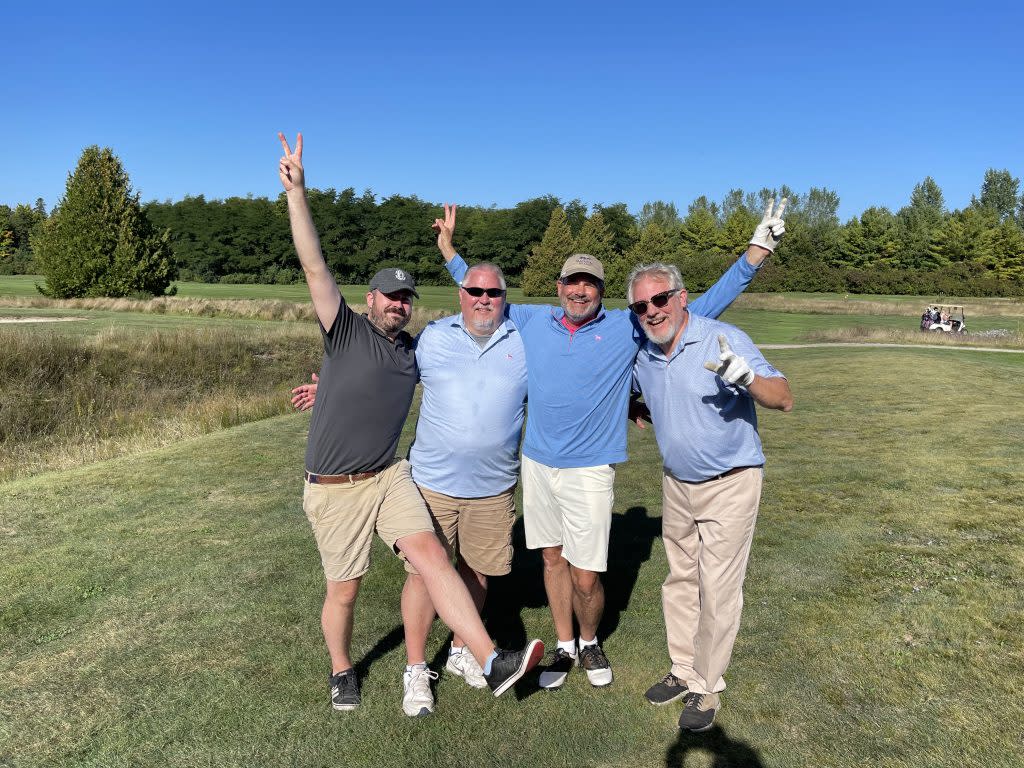 A foursome of golfers happily pose for a photo on the grounds of Mackinac Island’s Wawashkamo Golf Club