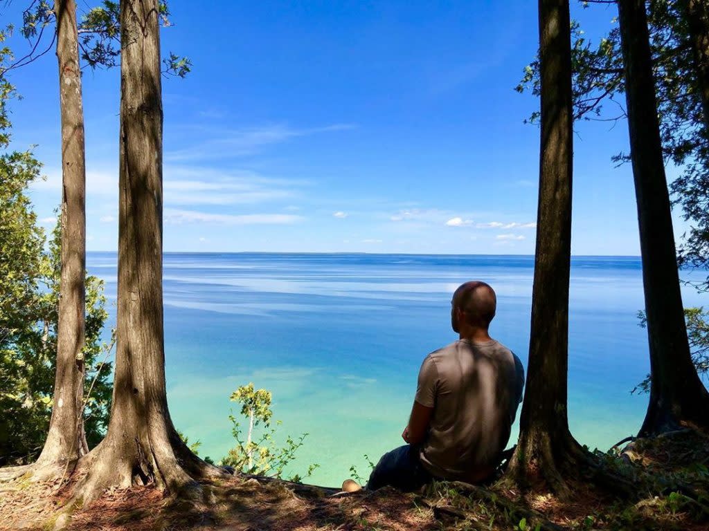 Man Sitting by Tree Enjoying View of Waters Surrounding Mackinac Island