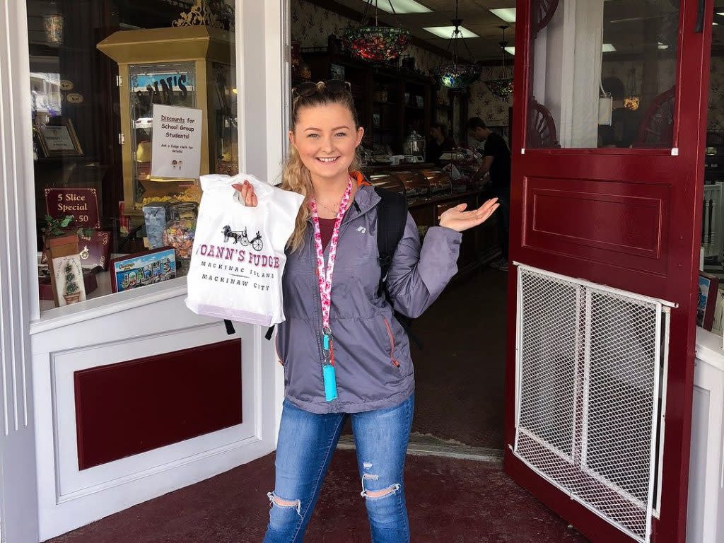 A young woman holds a bag of souvenir Mackinac Island fudge from Joann's Fudge