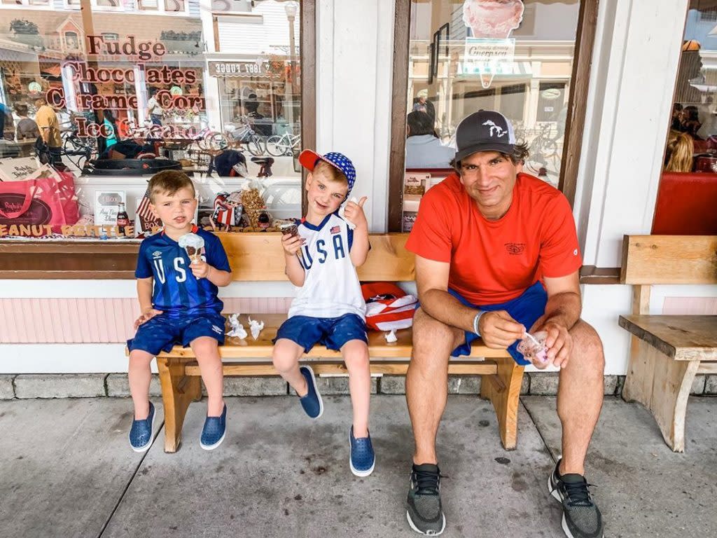 Dad and Two Sons Sitting on Bench Enjoying Fudge on Mackinac Island