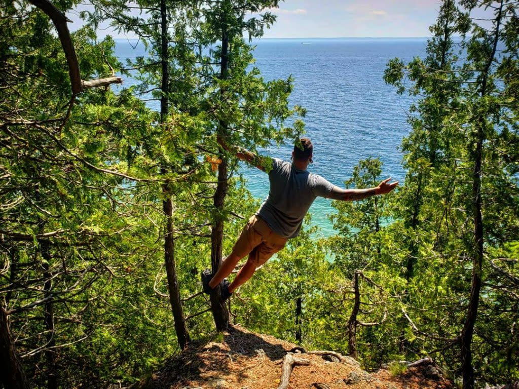 Man Swinging From Tree in Mackinac Island State Park Gazing at Horizon Surrounding Mackinac 