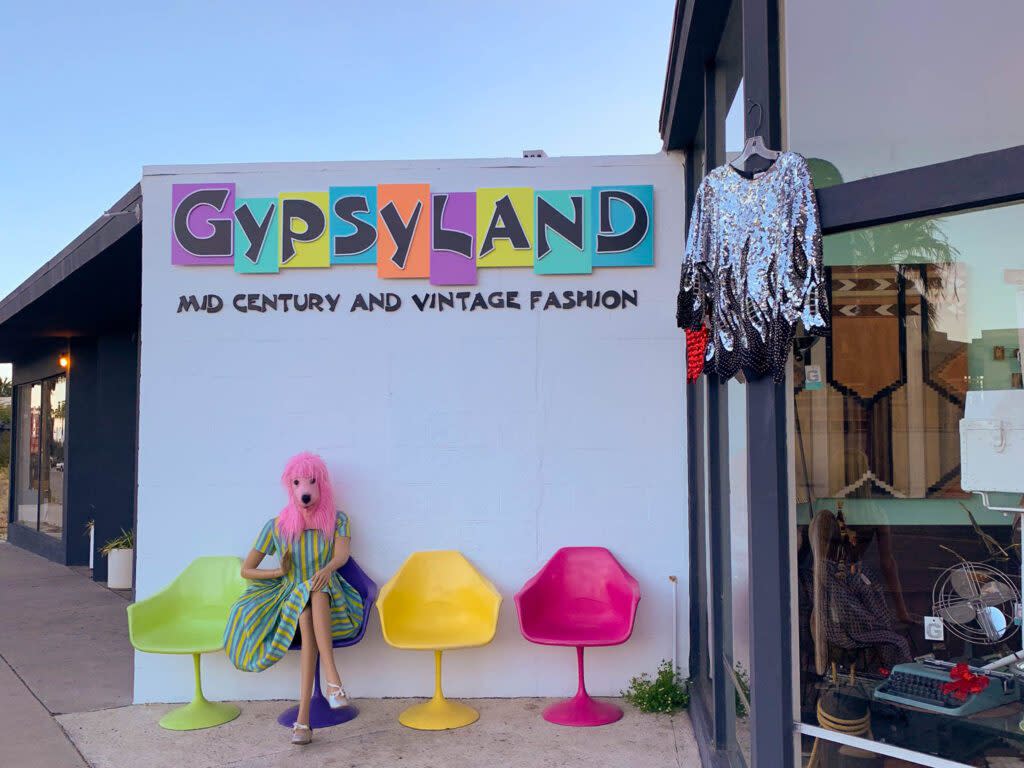 Gypsyland front signage. A woman is seated wearing a pink dog mask.
