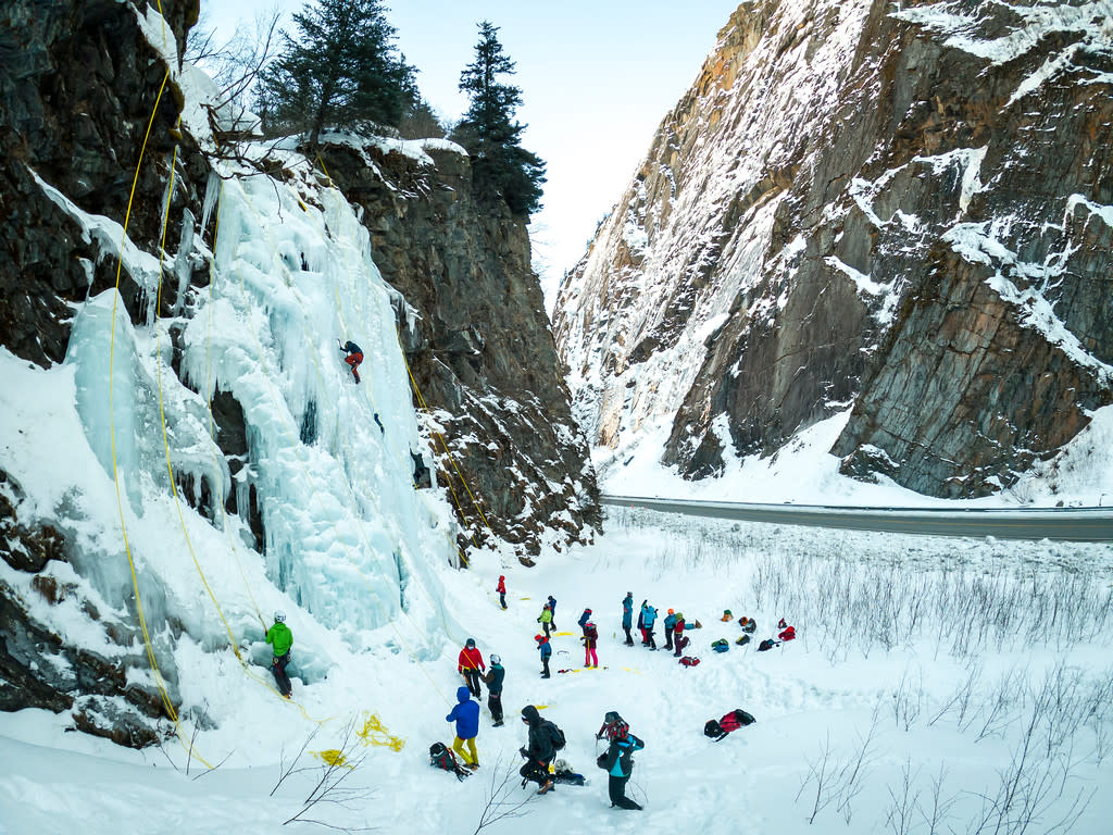 ice climbers ascend a frozen waterfall in a canyon