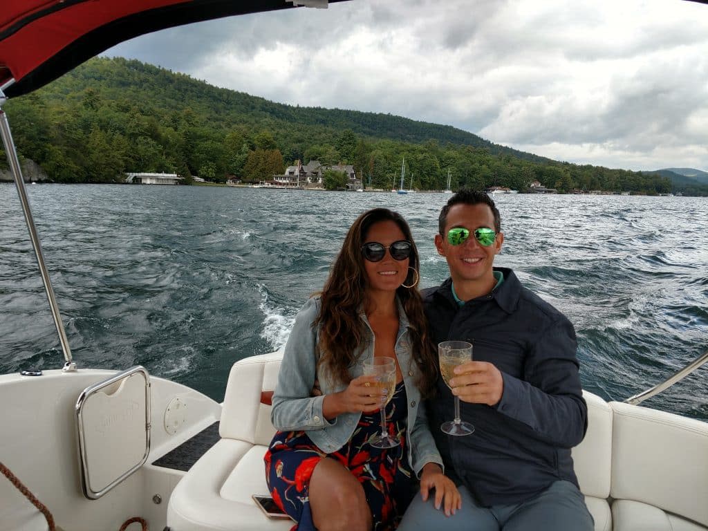 Couple enjoying wine on a Lake George Island Boat Tour with the Adirondacks in the background