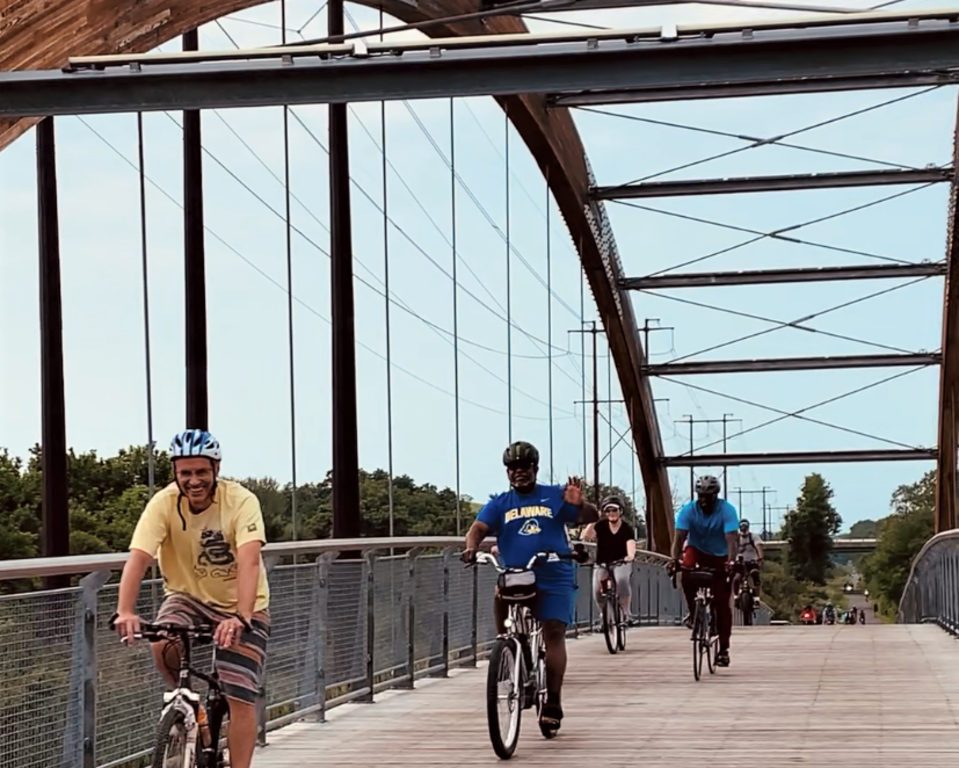 Bikers cross the Christina Pedestrian Bridge