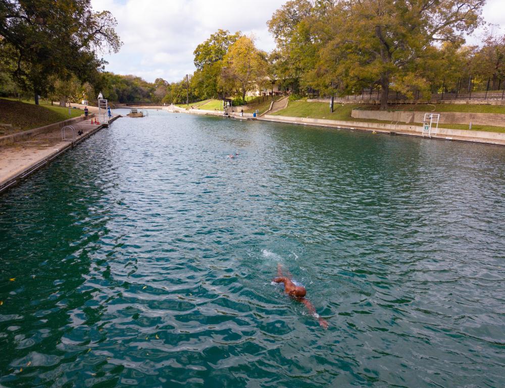 Man freestyle swimming in an empty Barton Springs Pool.