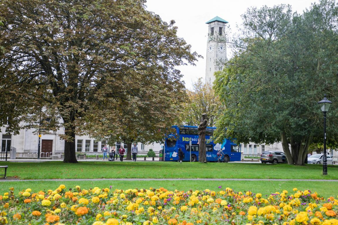 Watts Park in the summer with a flower bed of yellow and orange flowers surrouneded by green grass