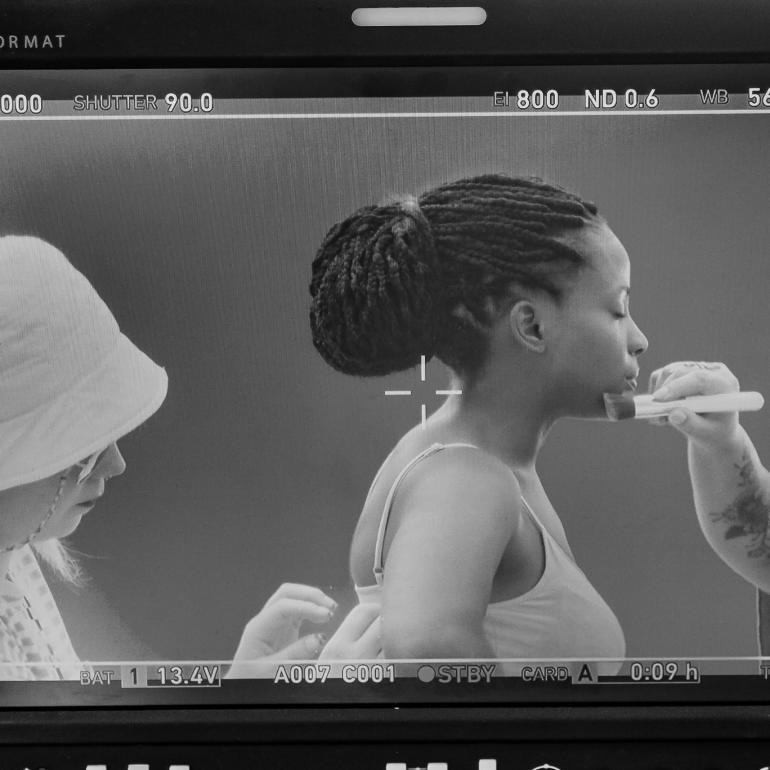 Beautiful young lady receiving makeup and costume touchups on camera.