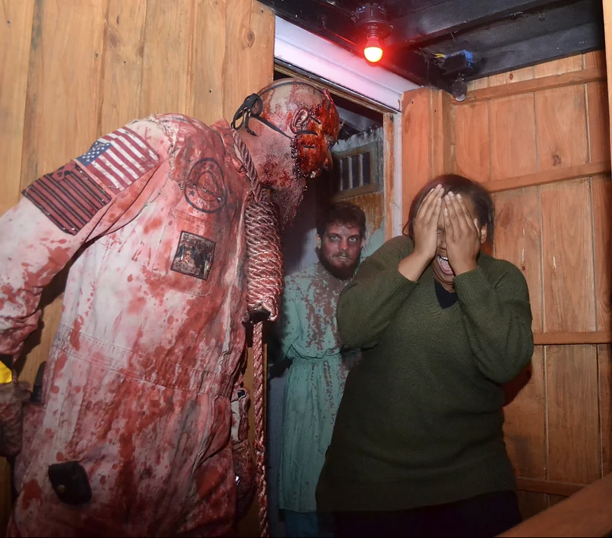 Guests walking through haunted trail attraction with costumed character