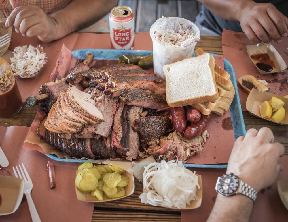 three men sit around a platter of BBQ and sides at Franklin Barbecue in Austin Texas