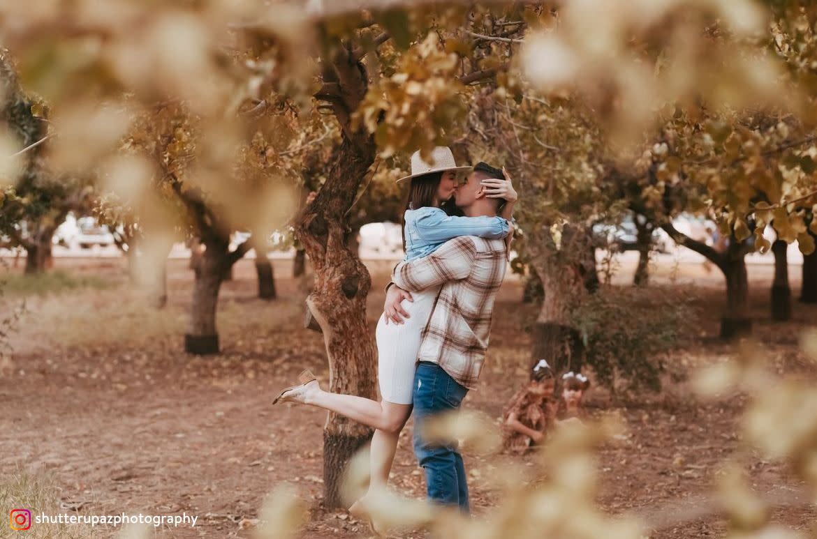 Couple kissing in a grove.