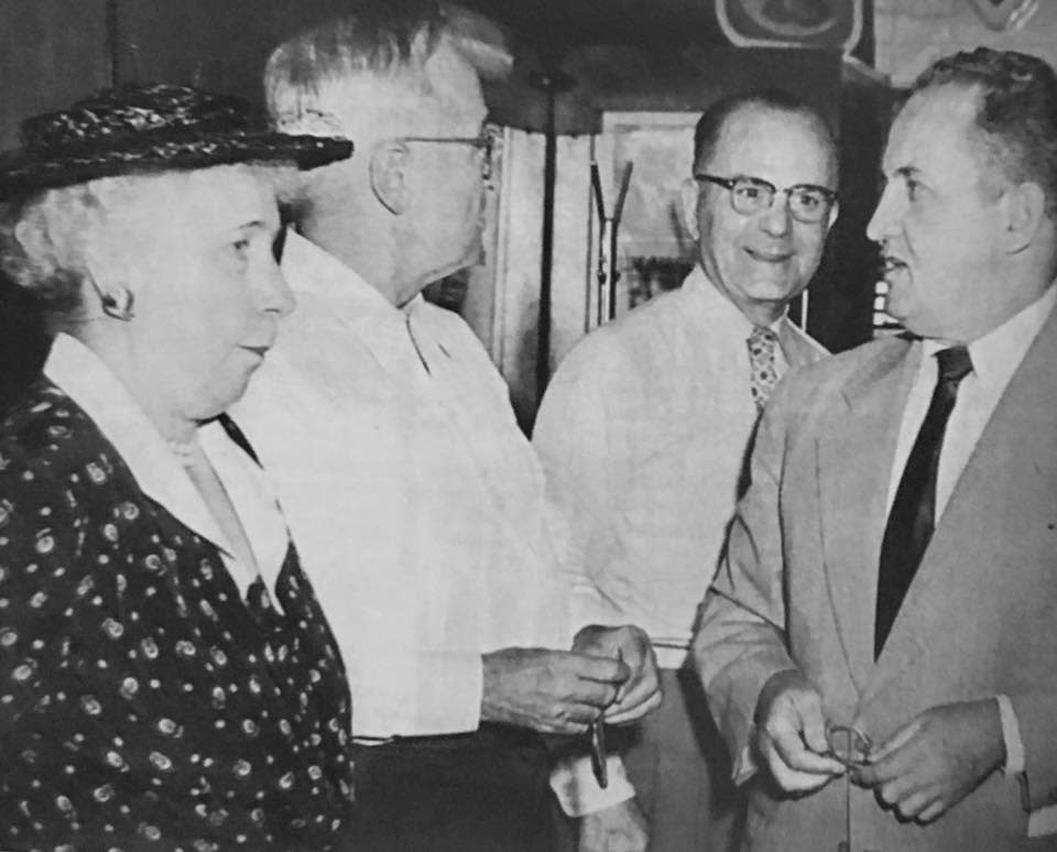 Black-and-white photograph of President Harry S. Truman speaking with three people inside the Princess Restaurant in Frostburg, Maryland; two men wear suits and glasses, and a woman wears a patterned dress and hat.