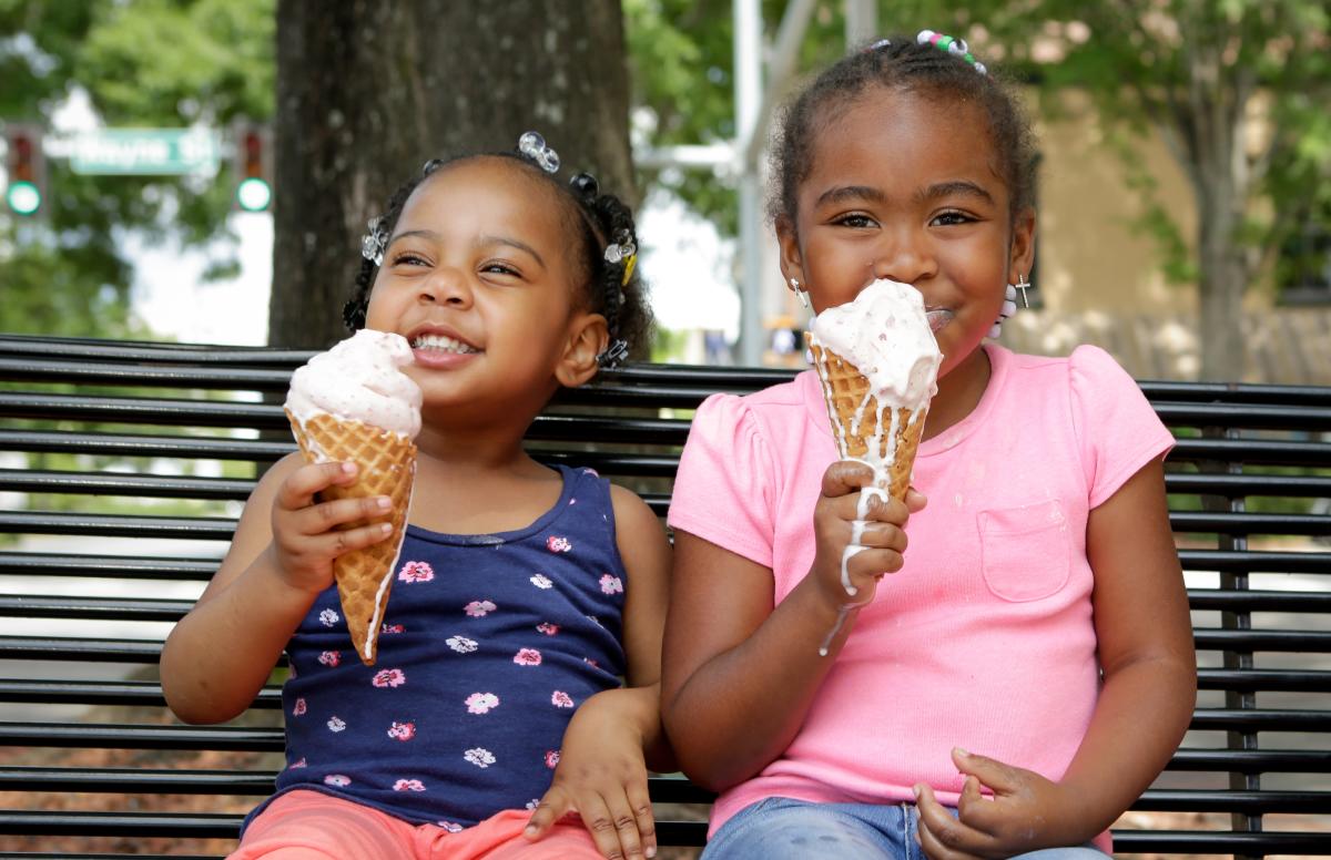 Little girls enjoying ice cream on a park bench