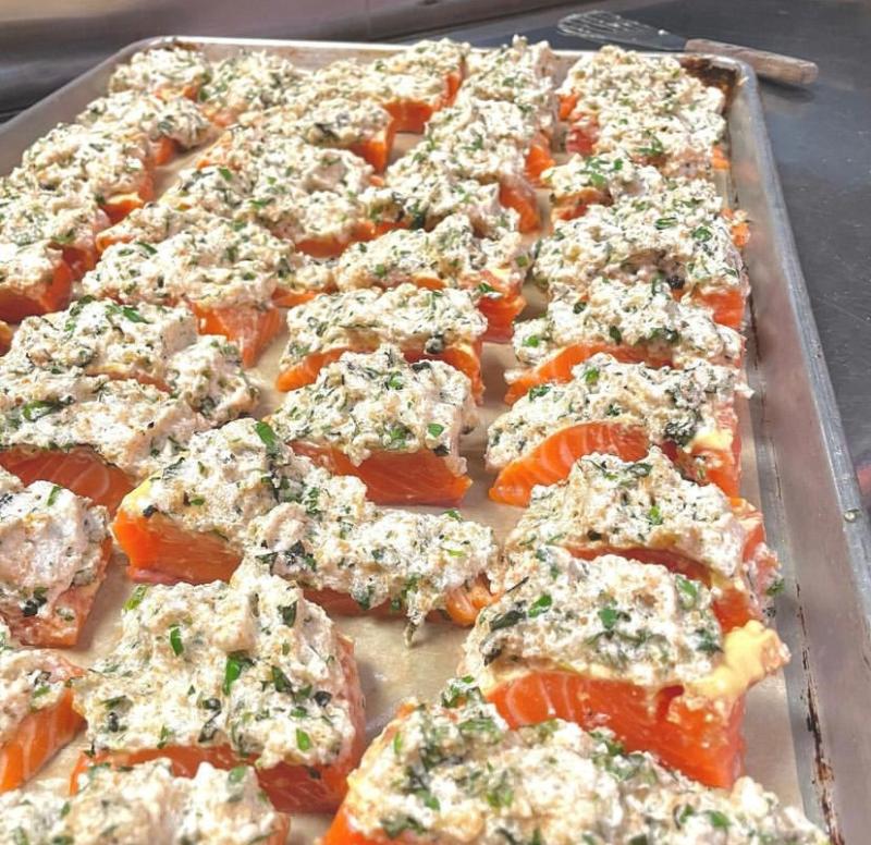 salmon on baking trays with compound butter on top ready to be baked