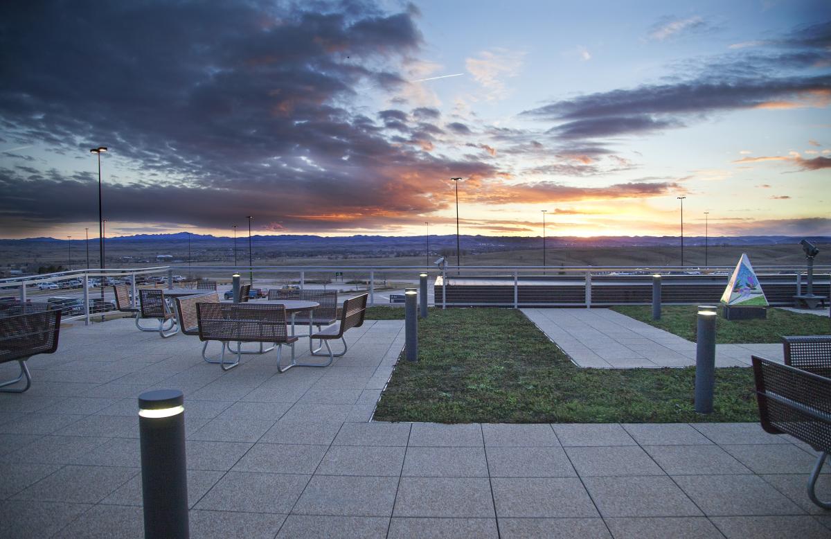 Outdoor patio seating at Rapid City Regional Airport overlooks the runway and Black Hills during a colorful sunset.