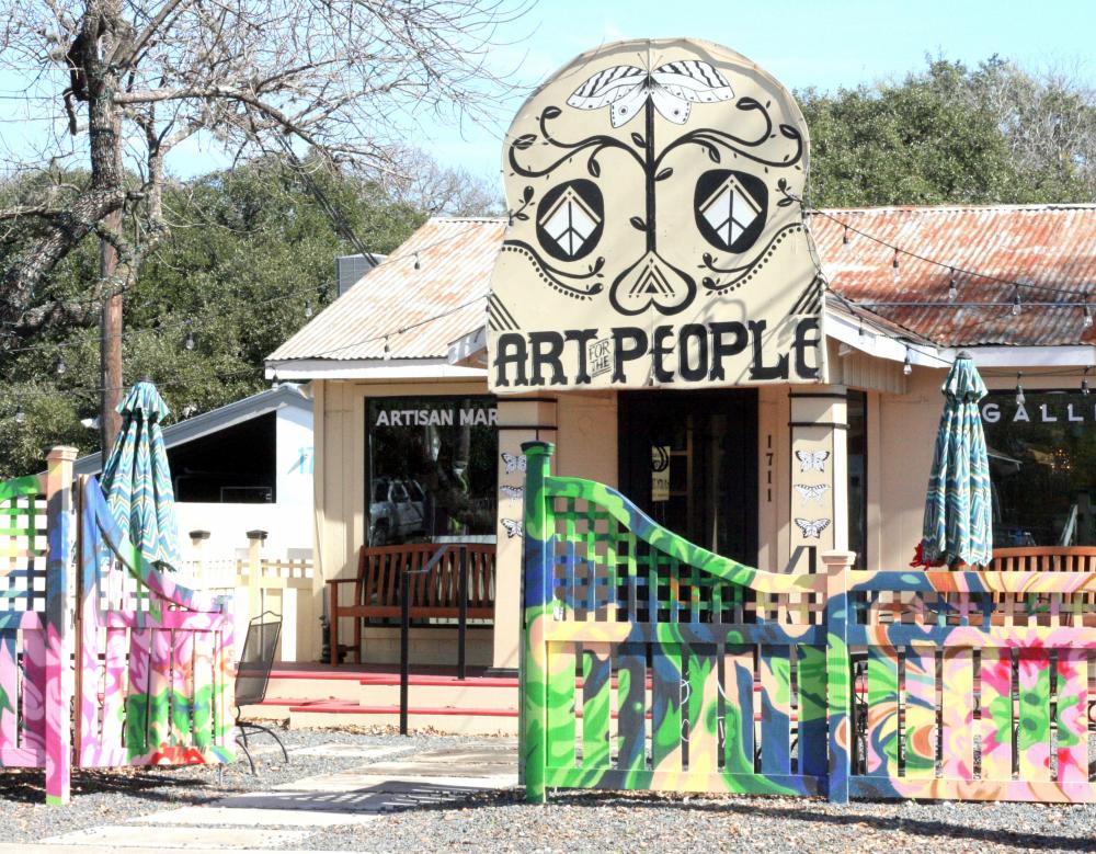 Exterior of Art for the People gallery with sign and painted fence in front of building