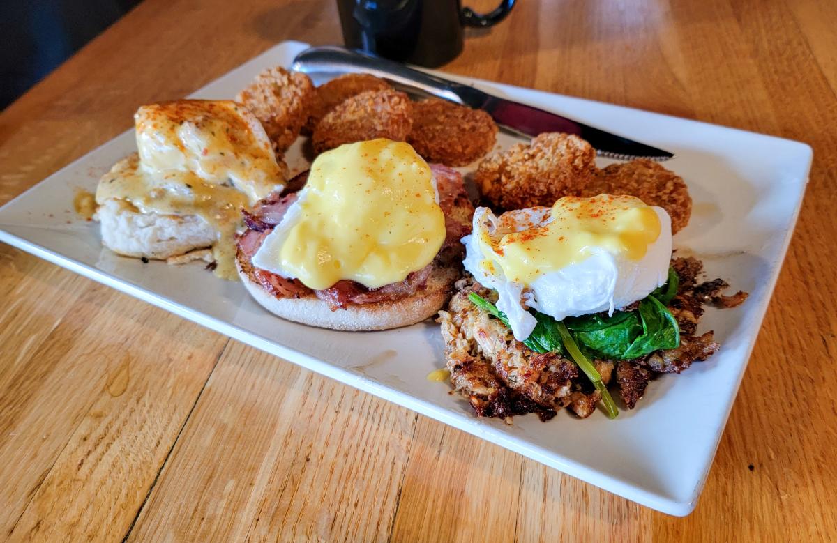 A square white plate with three different eggs benedicts and crispy hash browns.