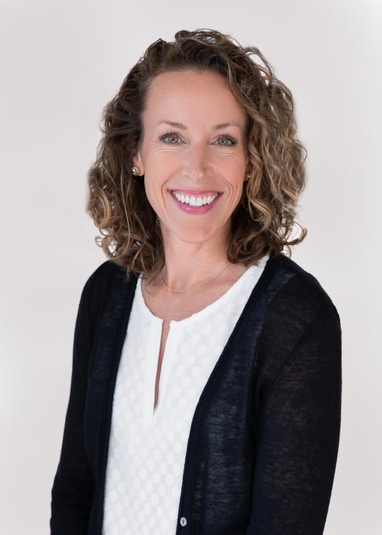Woman with a white shirt and black jacket smiles