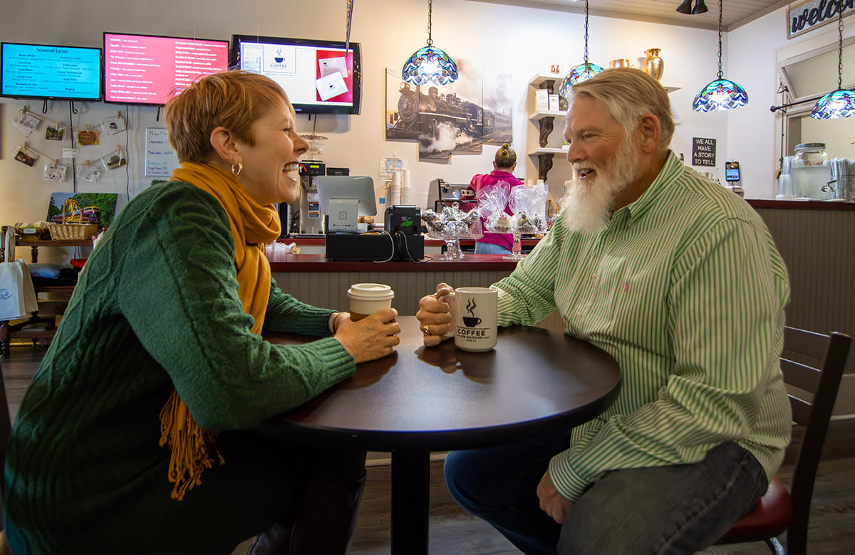 A woman and a man laugh while drinking coffee at a local coffeeshop in Selma.