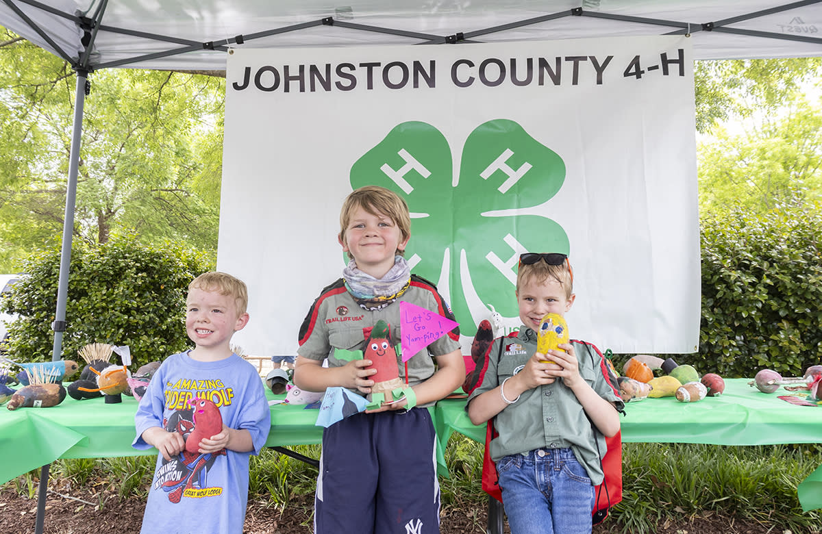 Three young boys showcase their decorated yams entered in the What's that Yam Thing? contest at the Ham and Yam Festival.
