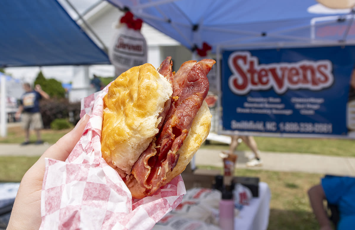 A ham biscuit is held up in a red and white foil wrap at the Ham & Yam Festival.