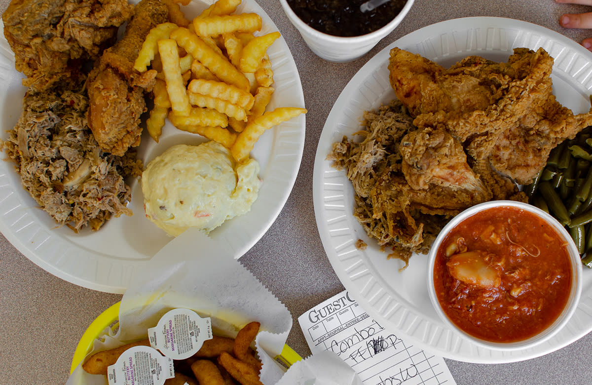 Pulled pork, french fries, fried chicken, potato salad, and hush puppies sits on a table at White Swan Bar-B-Q