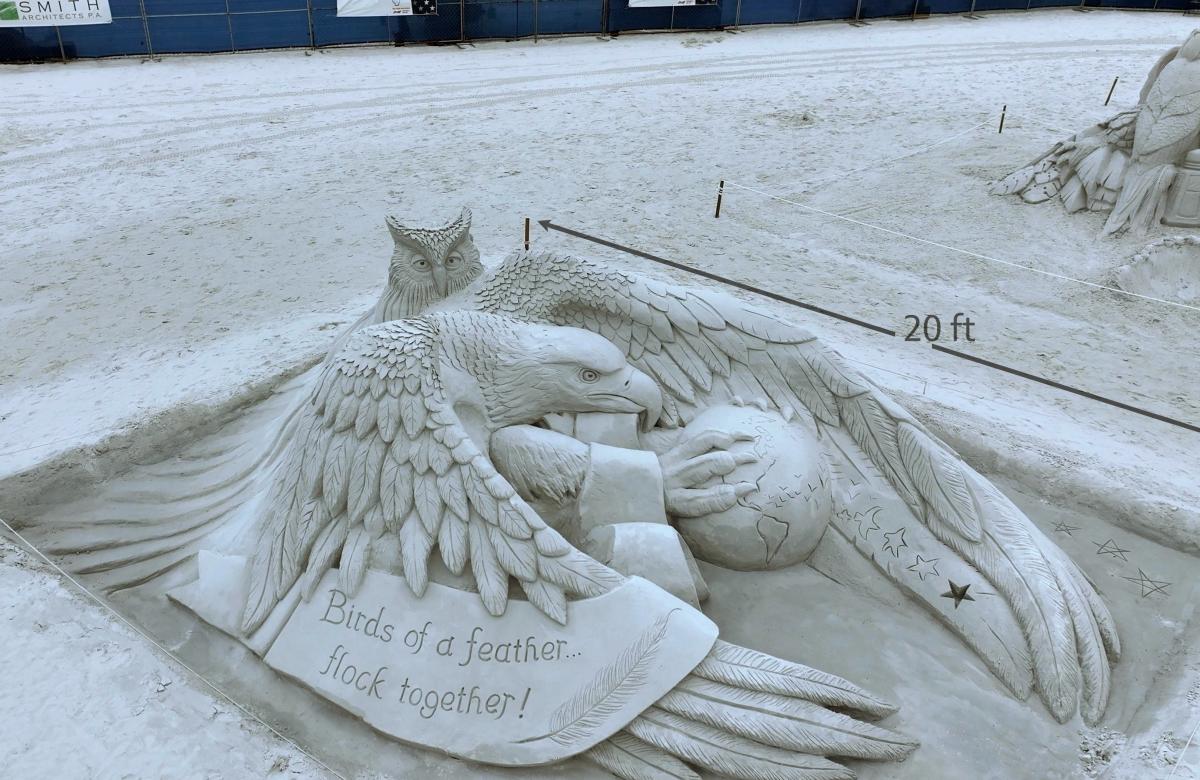 Sand sculpture of an eagle and an owl holding on to a globe