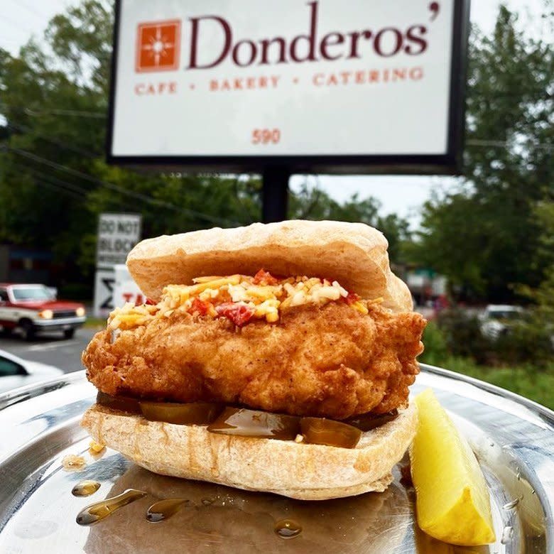 A sandwich from Donderos' Kitchen in front of the restaurant's sign.